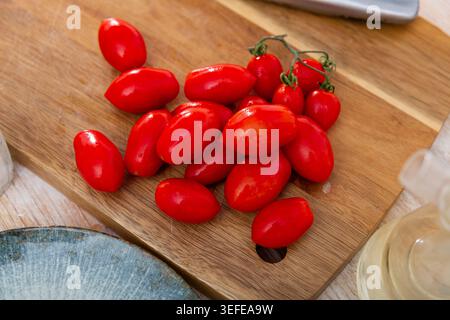Fresh ripe red plum-shaped cherry tomatoes on wooden table Stock Photo