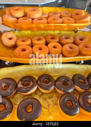 Buffet breakfast on cruise ship. A delicious buffet display of sweet glazed and chocolate covered donuts on golden trays. Stock Photo