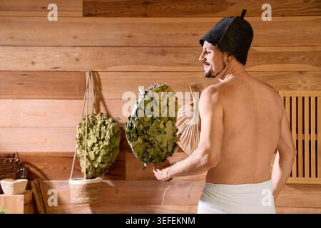 Handsome man with whisk in sauna, back view Stock Photo