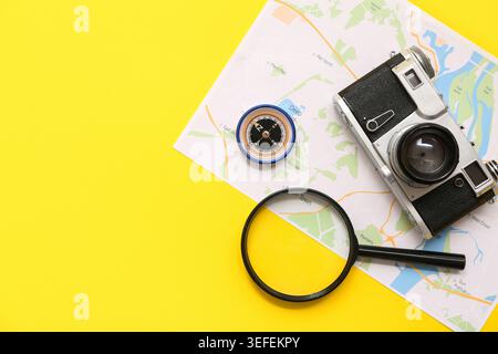 Composition with modern compass, world map, magnifier and photo camera on yellow background Stock Photo