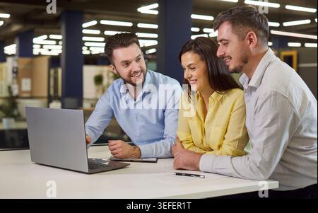 Couple looking at laptop screen standing at building market with salesman manager Stock Photo