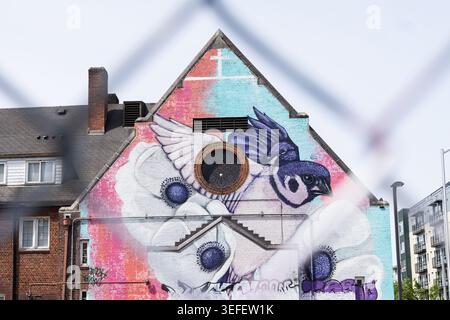 Colorful bird mural painted on the side of a building in an urban neighborhood Stock Photo