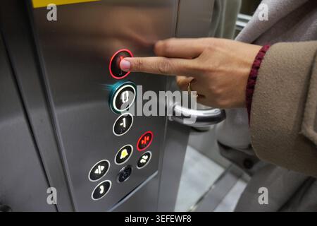 Person presses button in elevator at busy location Stock Photo