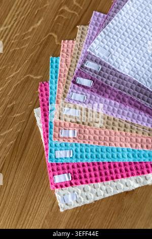 Fabric samples of different colors and textures are neatly stacked on a wooden table. Each piece displays a unique pattern suggesting options for craf Stock Photo
