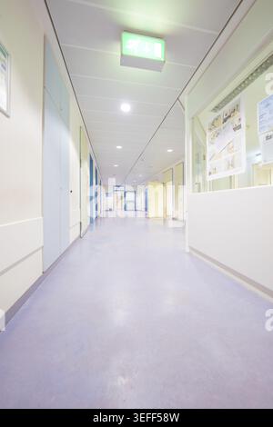 Bright and minimalistic corridor in a hospital, emergency exit sign on the ceiling, old disused hospital, Calw, Germany Stock Photo