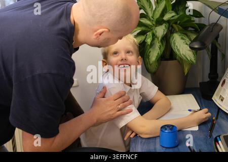 Father helping son with homework, encouraging learning and family bonding Stock Photo