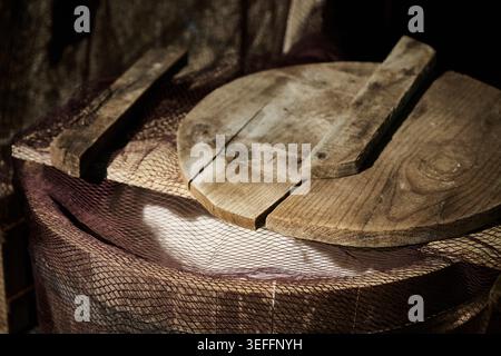 Old, textured wooden lid sitting on a traditional fishing net, presenting a worn surface and vintage atmosphere Stock Photo