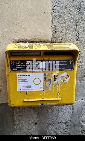 Old yellow French mailbox mounted on stone wall, Lyon, France. Stock Photo