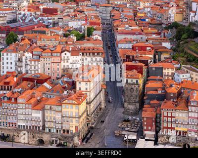 Drone view of Porto historic center in Portugal with a narrow city street, red rooftops, old buildings, and dense urban architecture at dawn Stock Photo