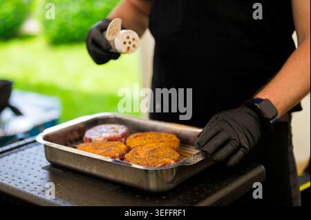 Close-up of a chef precisely seasoning a thick-cut ribeye steak with a spices on a cutting board during a professional Steak Cookoff Association (SCA Stock Photo