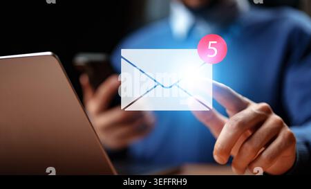 Checking email notifications on a computer and smartphone while working from home Stock Photo