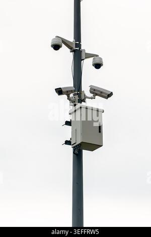 Professional surveillance system featuring dome and bullet cameras with a control box on a metal pole. Concept of public safety and urban monitoring. Stock Photo