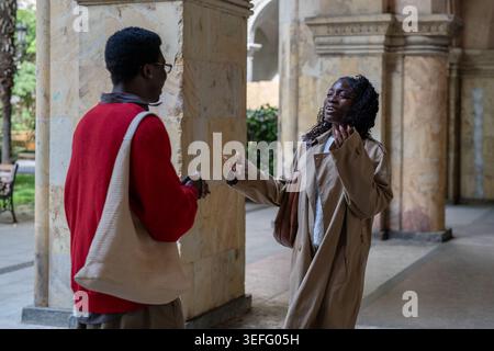 Cheerful surprised african american man and woman friends encountering each other at city street. Stock Photo