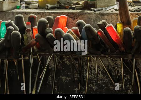 Close-up of various screwdrivers and hand tools stored on a workbench in an industrial workshop, showing organized chaos, craftsmanship and real worki Stock Photo