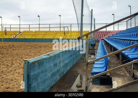 An empty beach volleyball stadium featuring a sand arena and colorful plastic seats after rain during the off-season. Concept of sports infrastructure Stock Photo