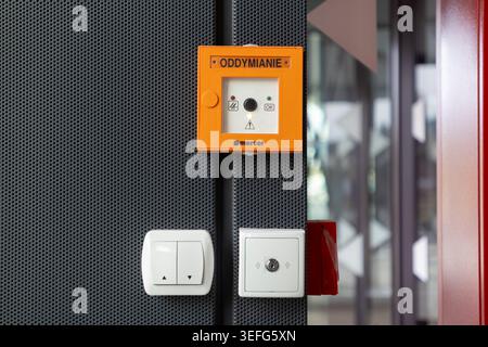 Warsaw, Poland - April 13, 2026: Orange fire ventilation switch on a perforated metal wall with electrical controllers, serving as a critical device f Stock Photo
