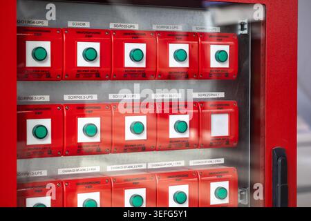 Warsaw, Poland - April 13, 2026: Grid of red industrial emergency push buttons on a control board with systematic labeling for electrical operations, Stock Photo