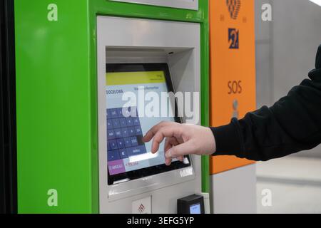 Warsaw, Poland - April 13, 2026: Close up of a passenger hand interacting with a digital station kiosk interface to purchase transport tickets, emphas Stock Photo