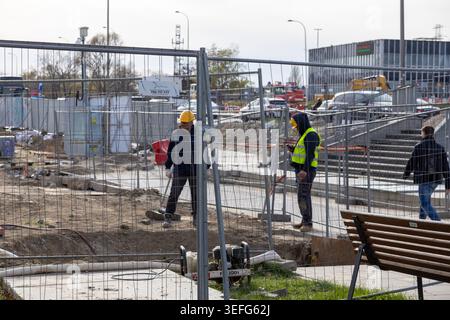 Warsaw, Poland - April 13, 2026: Professional construction workers in safety gear stand inside a cordoned building zone to represent civil engineering Stock Photo