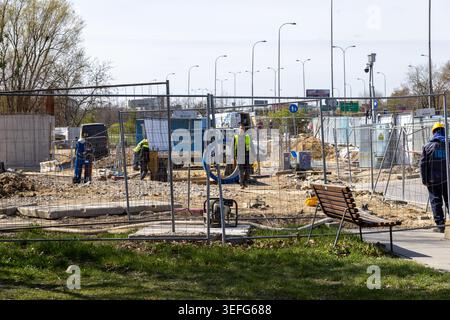 Warsaw, Poland - April 13, 2026: Construction site workers in yellow reflective safety gear walk at an outdoor urban renovation area, representing pro Stock Photo