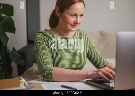 Comfortable remote work concept with woman using laptop from home Stock Photo