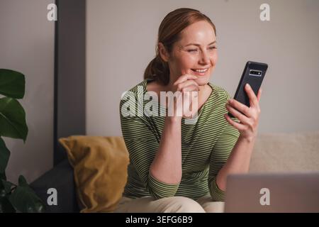 Successful online communication concept, smiling woman using phone Stock Photo
