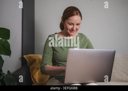 Comfortable remote work concept, woman using laptop from home Stock Photo
