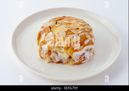 Sweet caramel almond cinnamon roll on a white plate Stock Photo
