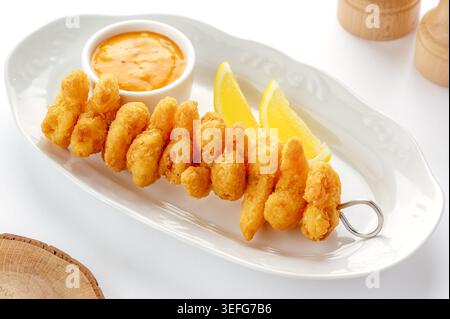 Fried shrimp skewer with dipping sauce and lemon wedges Stock Photo
