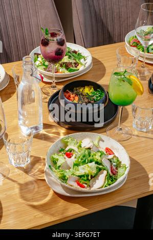 Assorted salads and drinks on a sunny restaurant table Stock Photo