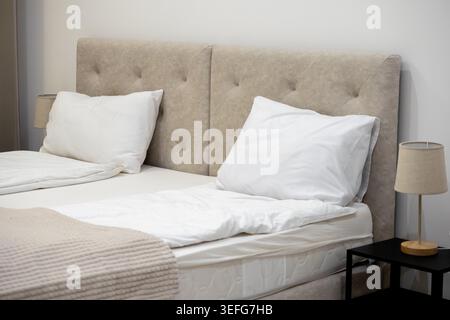 Close up of a comfortable double bed featuring crisp white linen and a plush tufted headboard, emphasizing serenity, hospitality, rest, and high-quali Stock Photo