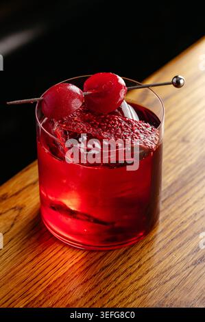 A vibrant red cocktail on a wooden bar top Stock Photo
