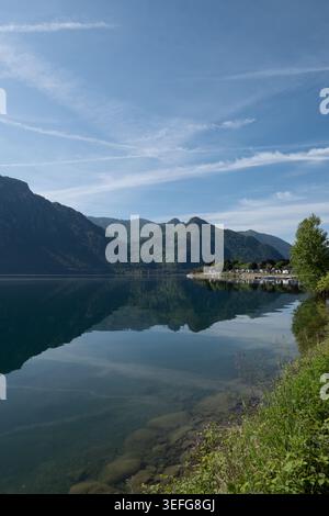 A quiet campsite overlooks the reflective waters of Lake Idro where green mountains and soft clouds create a peaceful natural landscape in northern It Stock Photo