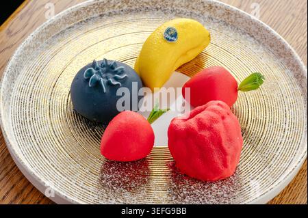 Assorted gourmet fruit shaped cakes on a gold platter Stock Photo