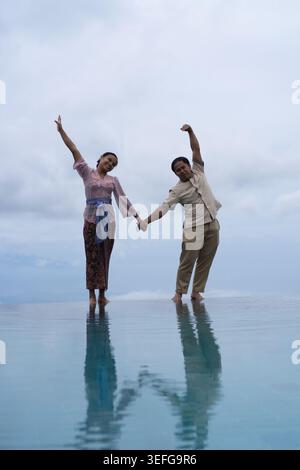 oyful Balinese couple making heart shape at infinity pool, Bali Stock Photo