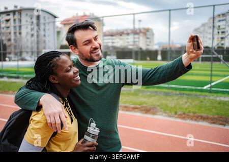 Diverse couple smiling, taking selfie after outdoor workout Stock Photo