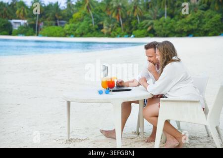 success business woman and man working in traveling, vacation with laptop. Workation by sea. Free freelancer workplace luxus outdoors in business trip Stock Photo