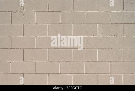 Close up of a painted cream cinder block and mortar wall surface with rough uneven chipped blocks, smooth and rough mortar joints Stock Photo