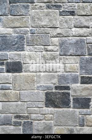 Close up of a rectangular rock block and mortar wall surface, with light to dark gray flat irregular blocks set in fitted rows Stock Photo