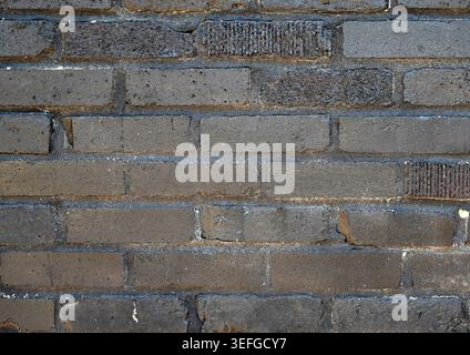 Reclaimed brick wall painted black with chipped and broken uneven bricks Stock Photo