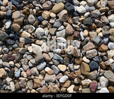 River rocks of various colors, shapes, and sizes in bright light, showing smooth and rough surfaces, mixed natural stones Stock Photo