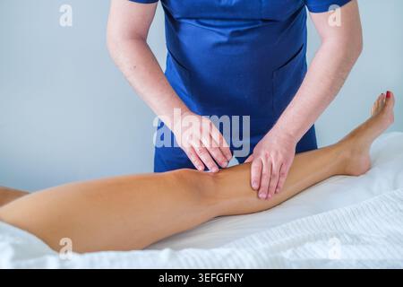 A woman receives a soothing calf massage from a skilled therapist using oil in a peaceful spa setting. Stock Photo