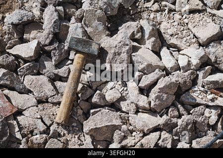 Heavy hammer resting on a rock, outdoor construction site background Stock Photo