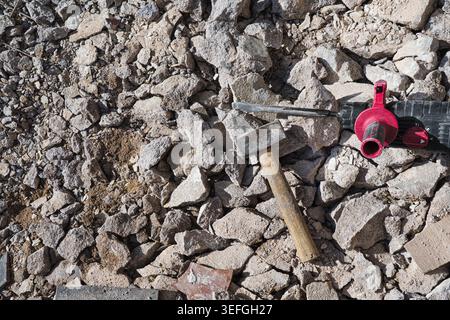 Heavy hammer resting on a rock, outdoor construction site background Stock Photo