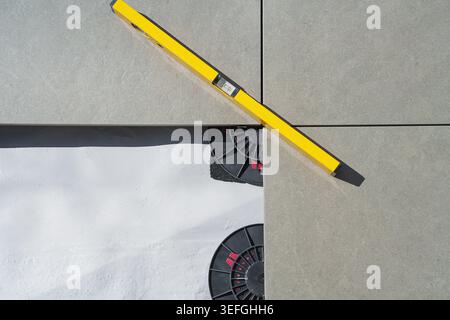 Laying tiles concept. Tiler, spatula and glue when laying tiles with close up hands. Stilts and pedestal supports for ceramic tiles to be laid on the Stock Photo
