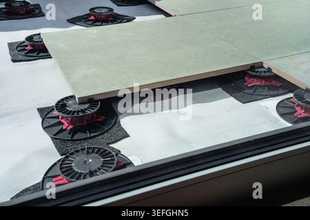 Laying tiles concept. Tiler, spatula and glue when laying tiles with close up hands. Stilts and pedestal supports for ceramic tiles to be laid on the Stock Photo