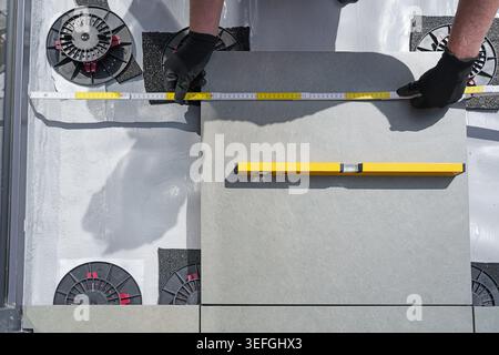 Laying tiles concept. Tiler, spatula and glue when laying tiles with close up hands. Stilts and pedestal supports for ceramic tiles to be laid on the Stock Photo