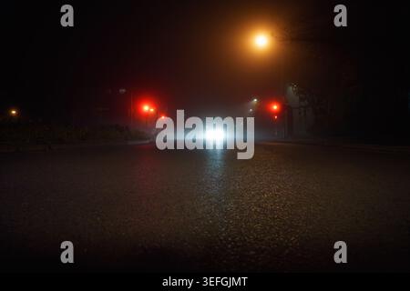 Road traffic in fog at night. Diffuse car headlights at night. Stock Photo