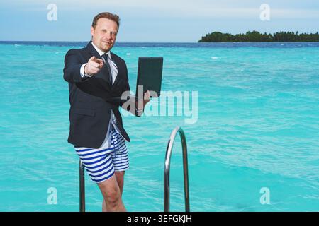 Remote online working on summer luxus sea beach. Business man with laptop during tropical beach vacation. Crazy comic businessman success concept. Stock Photo