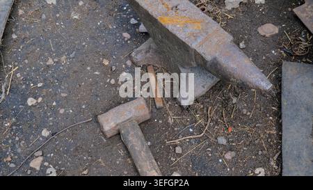 Old Rusty Blacksmith Anvil with Hammer in Workshop Stock Photo